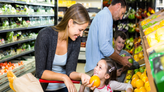 Woman with her child in the supermarket looking at oranges