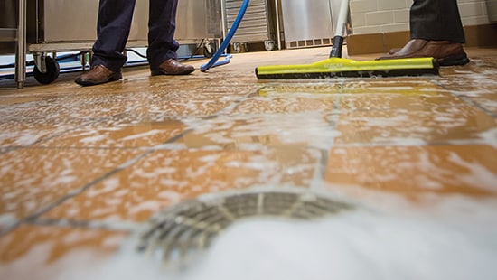 Closeup of floor being cleaned emptying into a drain