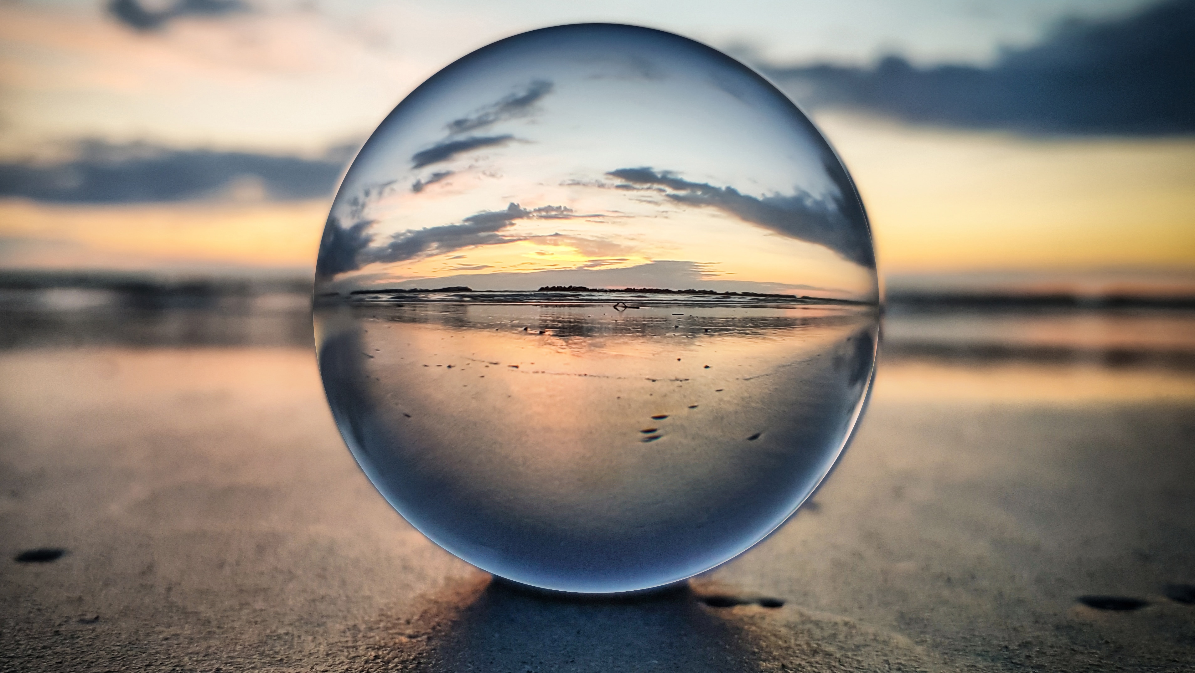 Glass sphere on a beach at sunset