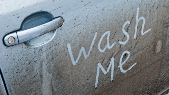 dirty car with wash me written on the side